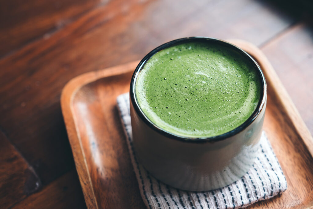 a cup of hot matcha latte on wooden floor